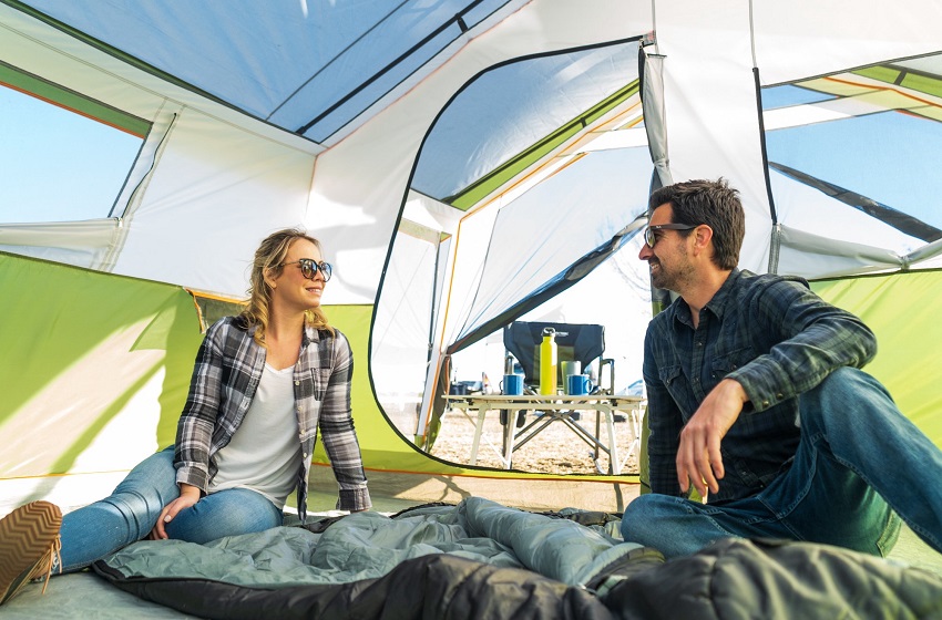 A man and a woman sit inside the Ozark Trail 8-Person Family Cabin Tent with Screen Porch