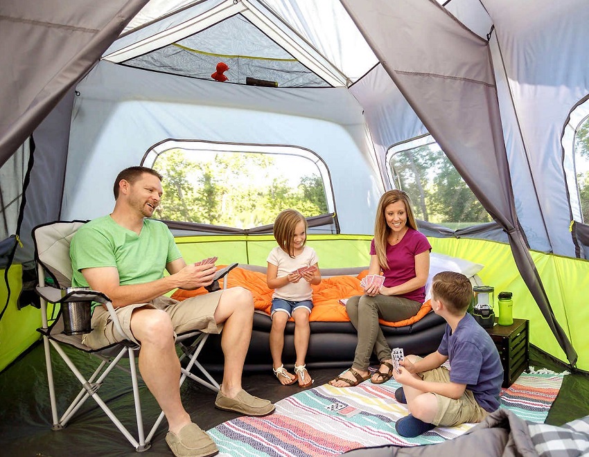 A family is playing cards inside the CORE 10-Person Instant Cabin Tent