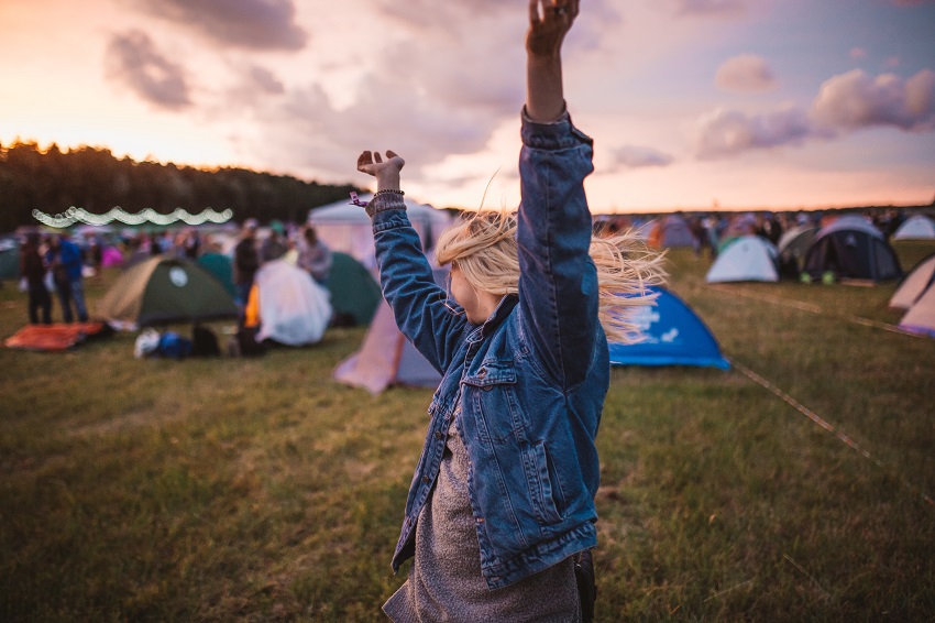 A dancing girl with a crowded campsite behind her