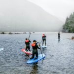A group of people paddles boards of different colors and sizes
