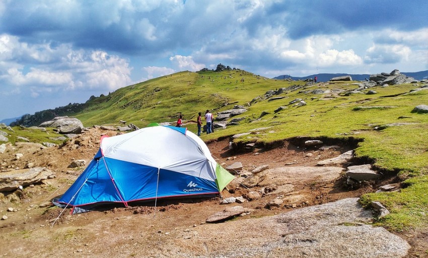 A white and blue tent is pitched on a hill
