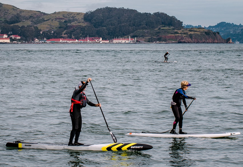 A man and a woman paddle racing paddle boards on water