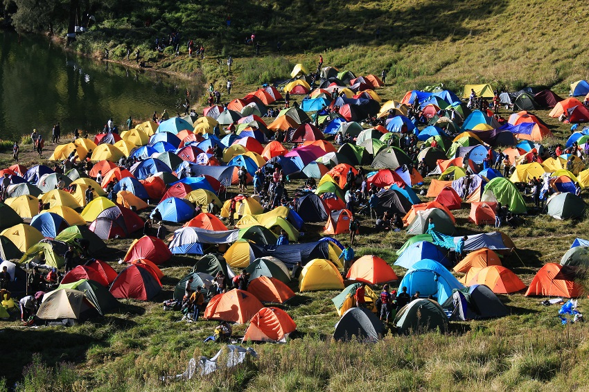 A busy campground with multiple tents of different colors