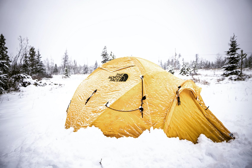 A yellow The North Face camping tent is pitched on the snow