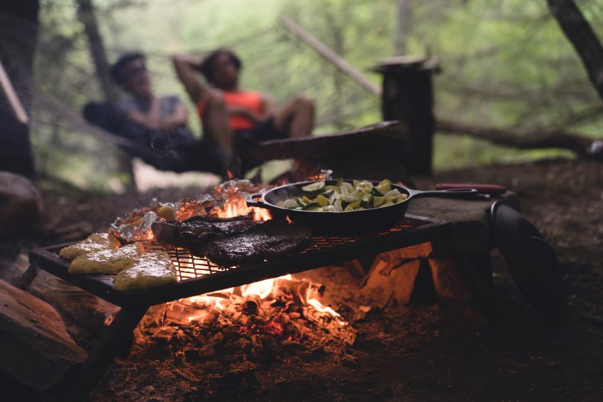 Food is cooked on a grille over a campfire