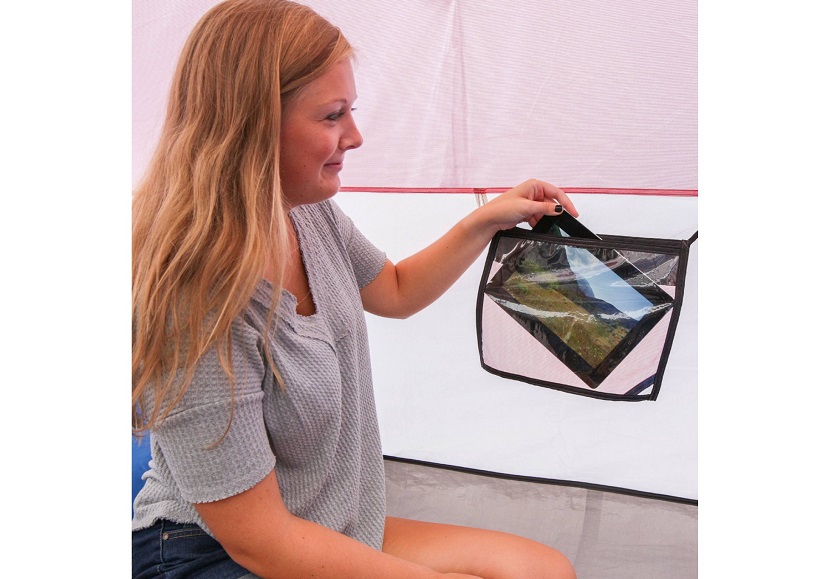 A woman puts her tablet PC in a storage pocket inside the Ozark Trail 6 Person Dome Outdoor Camping tent