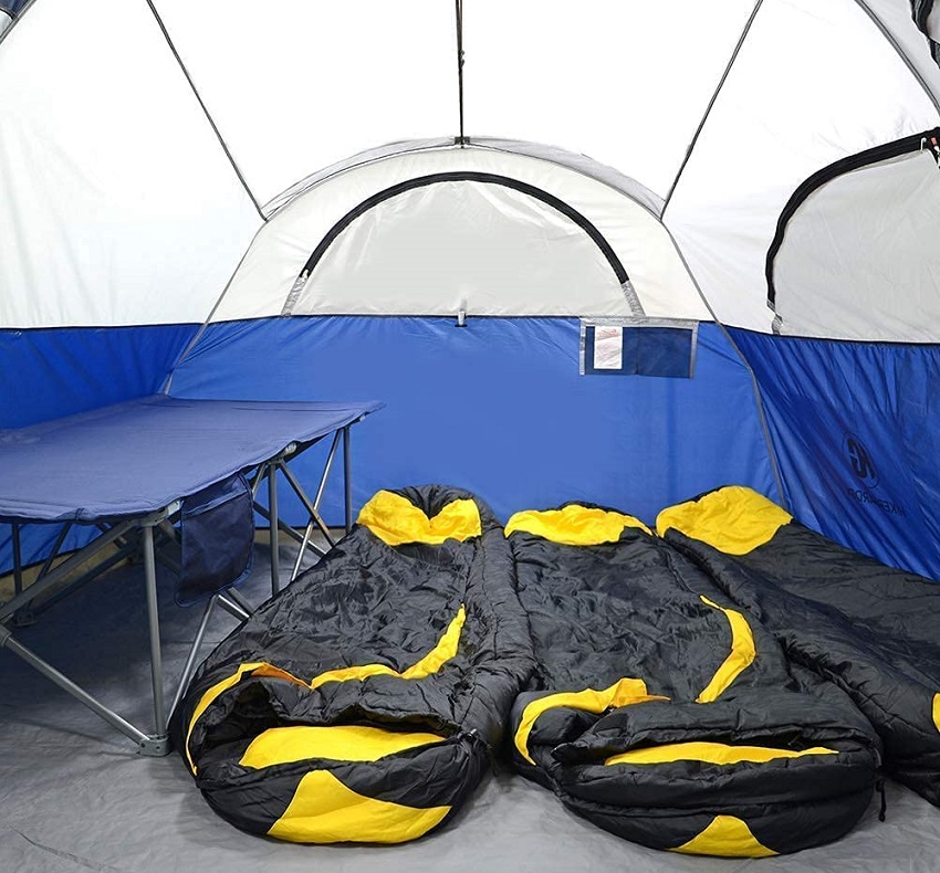 Three black and yellow sleeping bags and a camping table inside the CAMPROS CP Tent