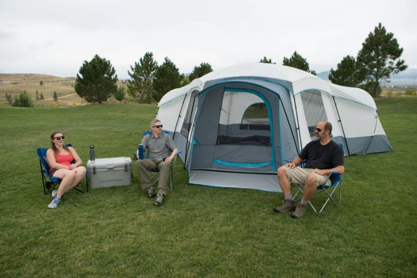 Three people sit in camping chairs near the Ozark Trail 16-Person Cabin Tent