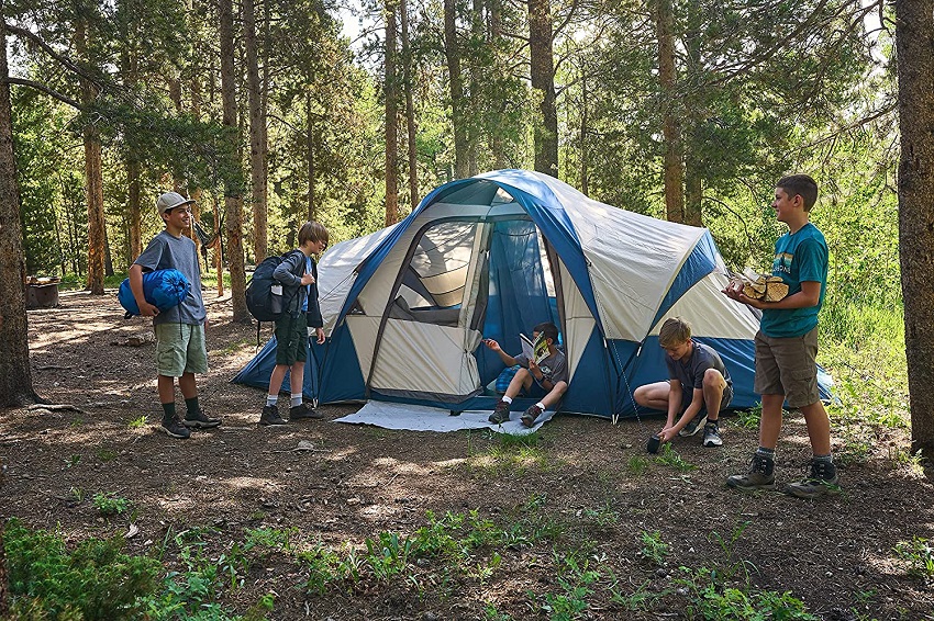 A company of boys is preparing their campsite with the Wenzel Pinyon 10 Person Dome Tent