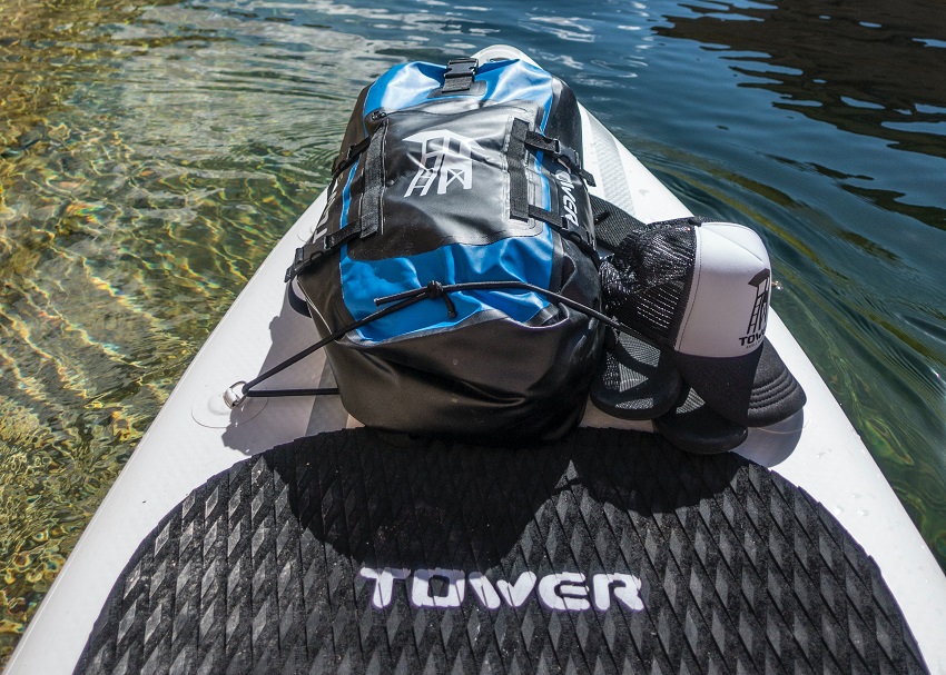 A paddle board with a dry bag and a cap on it