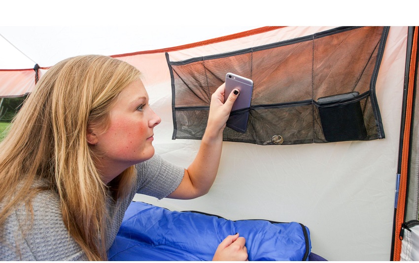 A girl puts her smartphone into a mesh storage pocket inside the Ozark Trail 8 Person Yurt Camping Tent