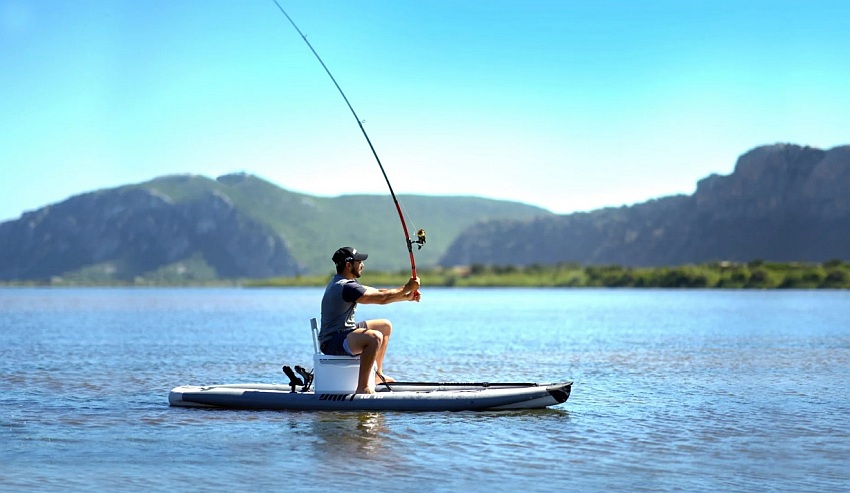 A man casts a spinning rod from a paddle board