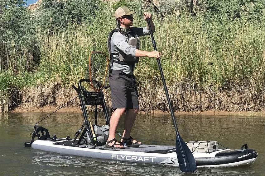 An angler stands on a paddle board loaded with fishing gear
