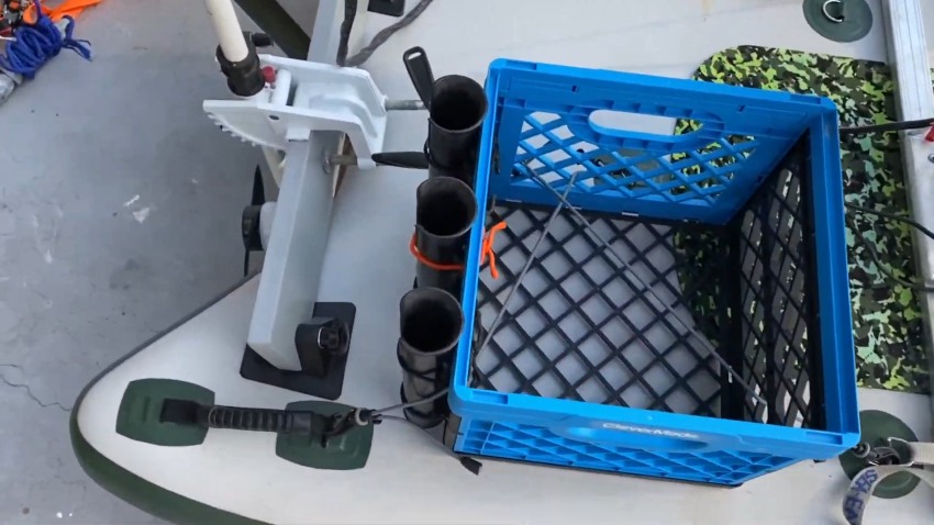 A crate with three fishing rod holders is attached to a paddleboard