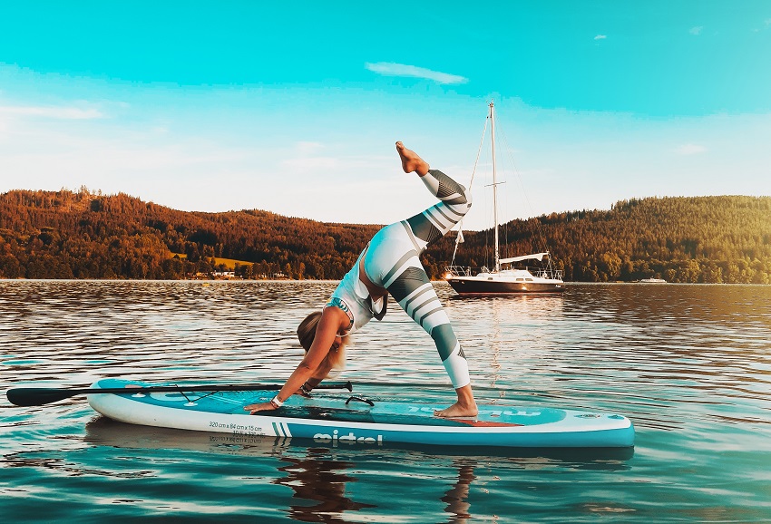 A woman practices yoga on her SUP in the middle of lake