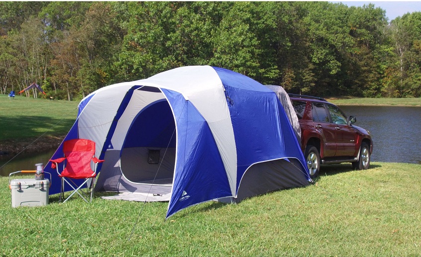 White and blue Ozark Trail 5-Person Dome Tent, attached to a red SUV 