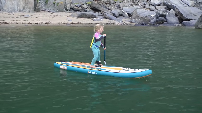 A small girl paddles a blue paddle board