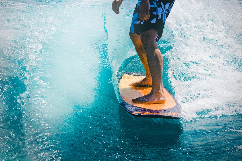 A man catches the wave on an orange surfing paddle board