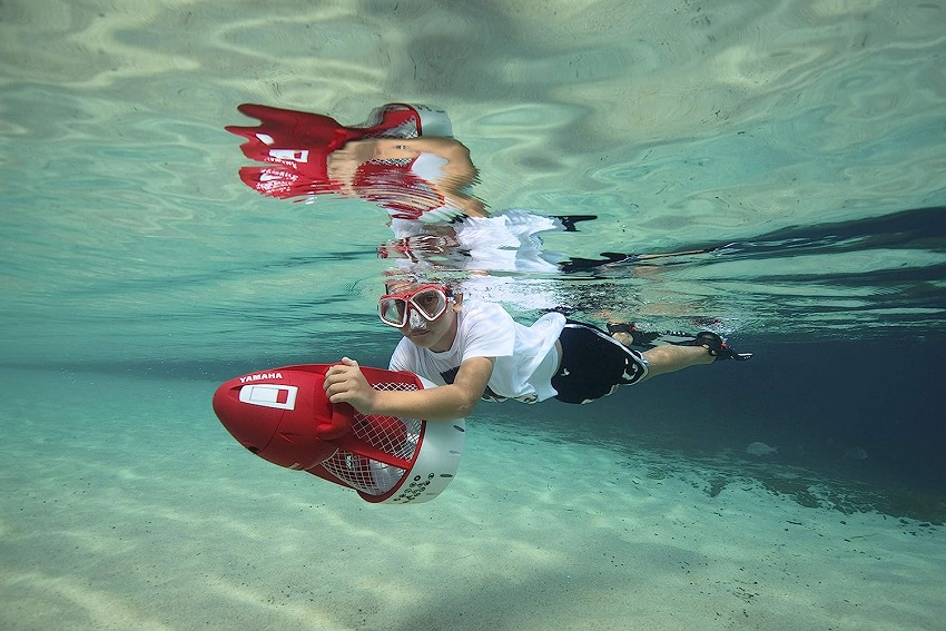 A boy rides the red Yamaha underwater scooter
