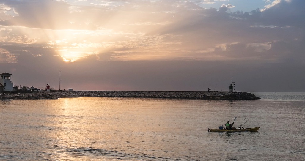 An angler paddles his fishing kaya at sunset 