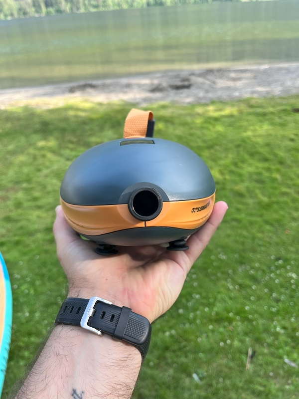 A human hand holds the OutdoorMaster Dolphin SUP pump