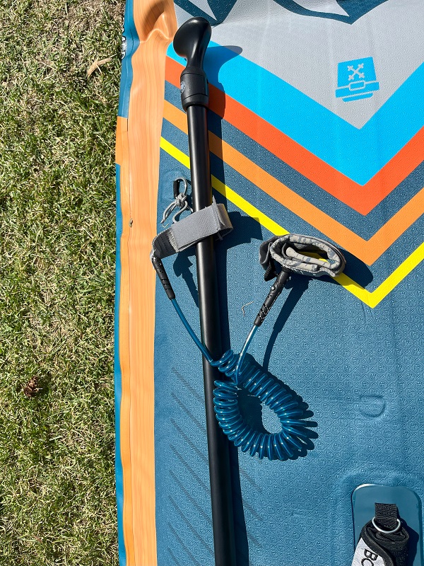 A Velcro-strap on a leash holds a paddle on the BodyGlove Performer 11 Inflatable SUP