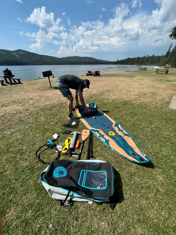 Author unfolds the BodyGlove Performer 11 Inflatable SUP on a lake shore 