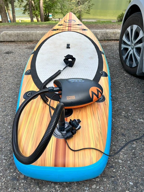 OutdoorMaster Shark II SUP pump is connected to a paddle board