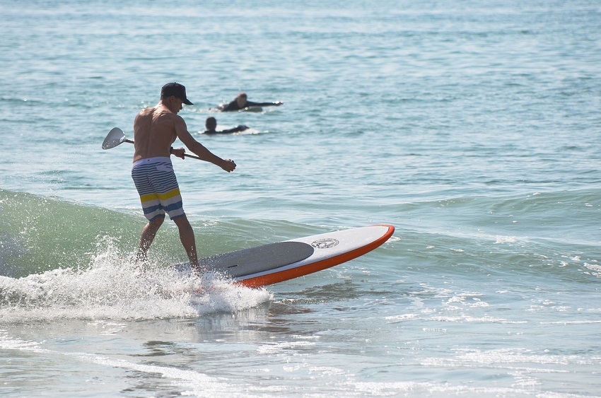 A man surfs a wave on his paddle board