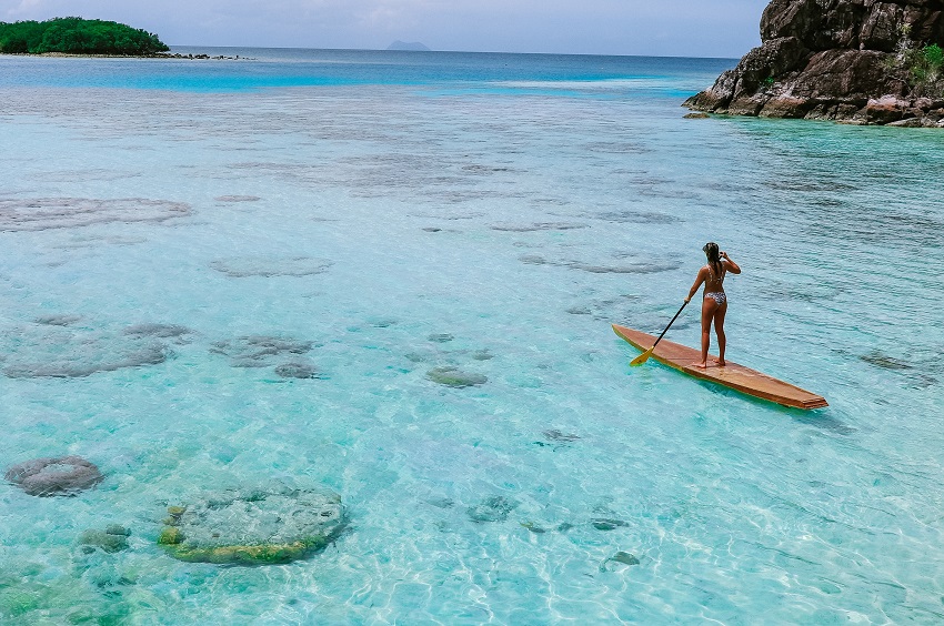 A woman paddles a wooden SUP on blue water
