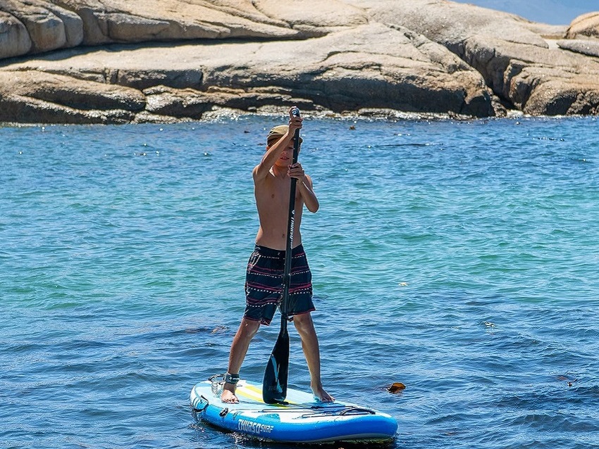 A boy paddles an inflatable SUP